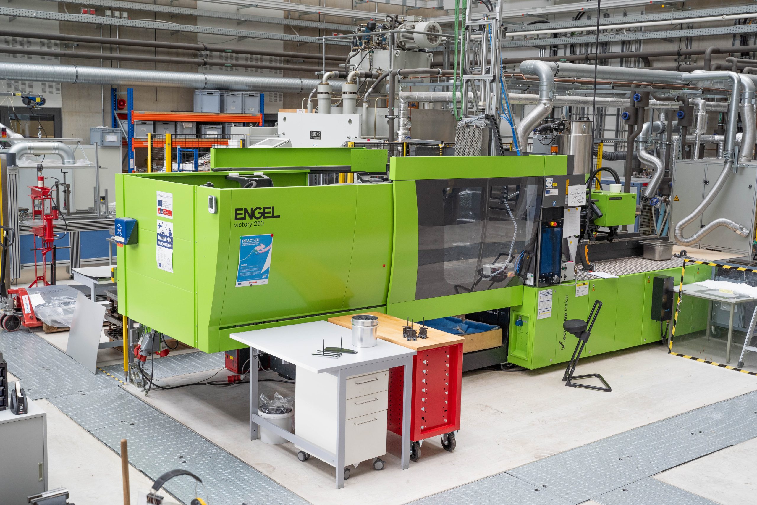 Eine grüne Maschine steht in einer Werkstatthalle
