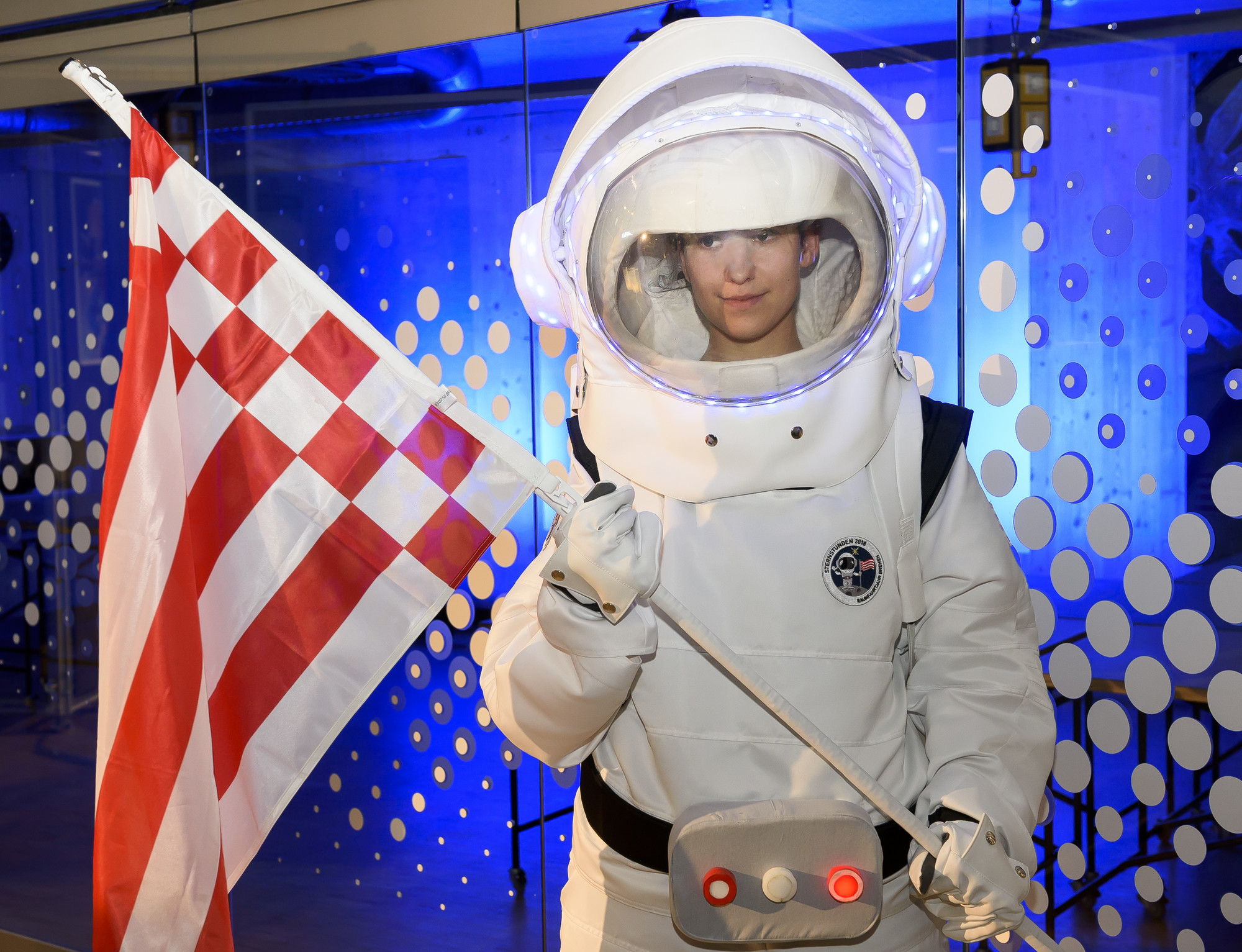 Ein Kind in einem Astronautenanzug hält eine Flagge